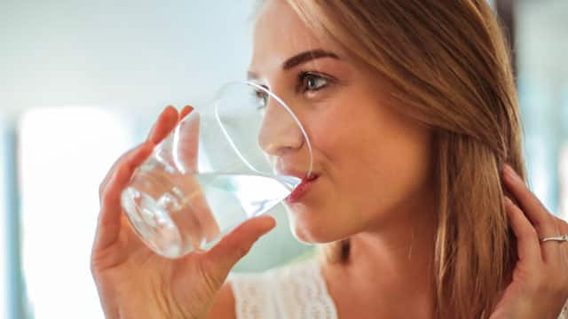 A woman drinking a glass of water.