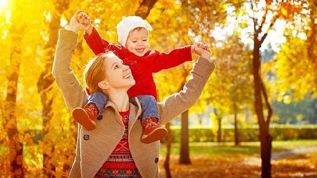 mother smiling giving her child a piggyback outdoor