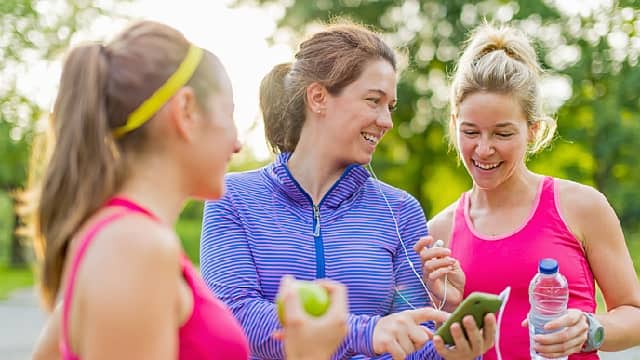 Athletic ladies laughing at phone outdoors