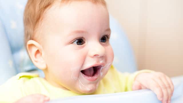 baby laughing with a mouth cover with food