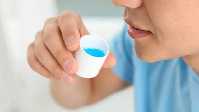 Closeup of a man sipping mouthwash.