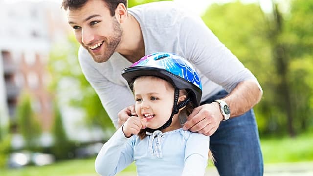 Padre enseñando a su hija como montar en bicicleta