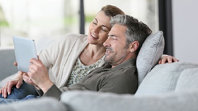 a man and a woman smiling while looking at the tablet