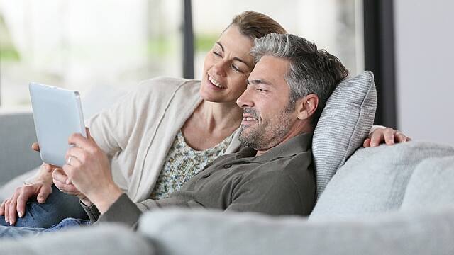 a man and a woman smiling while looking at the tablet