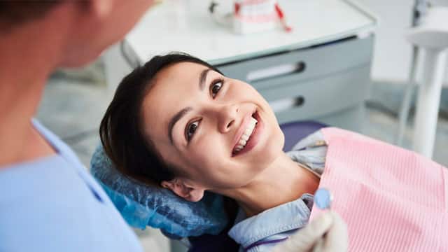 Woman smiling in an office while having her teeth examined