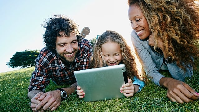 Parents and kid looking at tablet happily