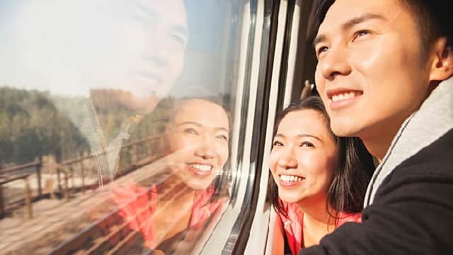 a man and a woman smiling brightly while looking out the train window