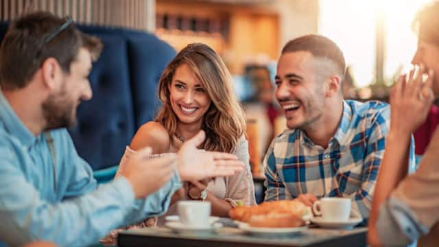 A group of friends smiling and talking at a restaurant.