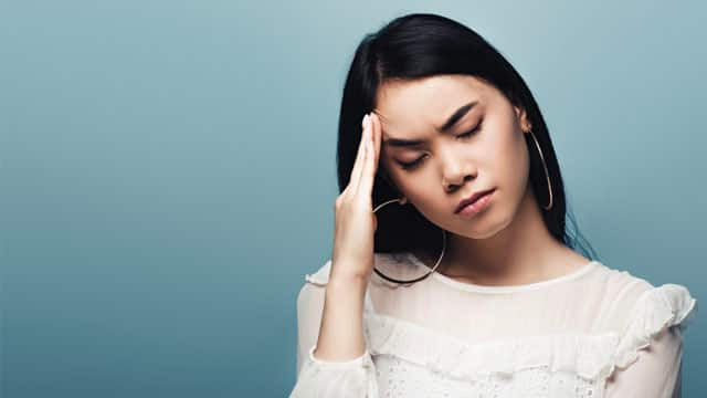 A woman holding her head, not feeling well.