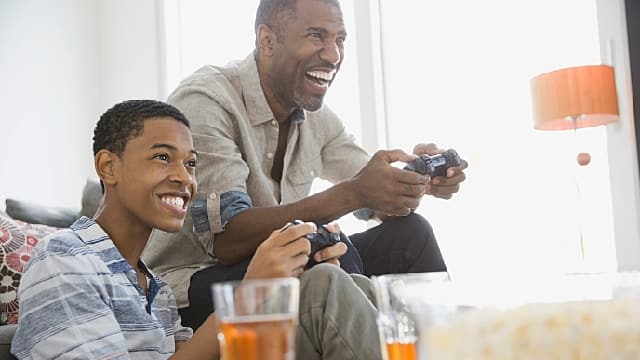 Father and son playing video games together at home