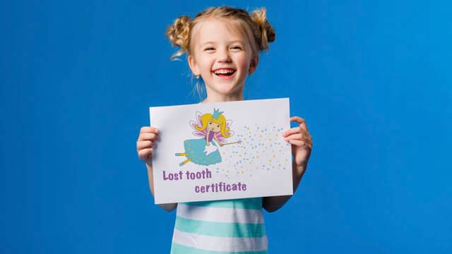 Young girl smiling and holding a tooth fairy certificate.