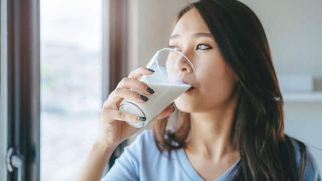 A woman drinking a glass of milk. A woman drinking a glass of milk.