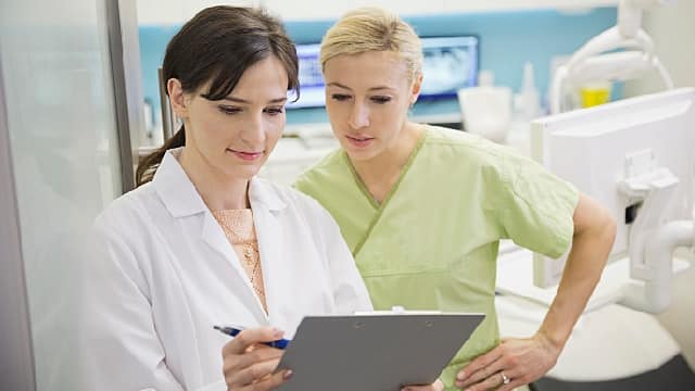 a dentist and a dentist assistant looking at a chart