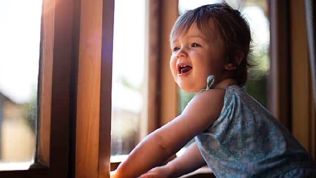 Baby looking out window with smile