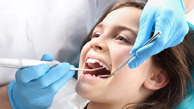 young girl having her teeth examined by a dentist