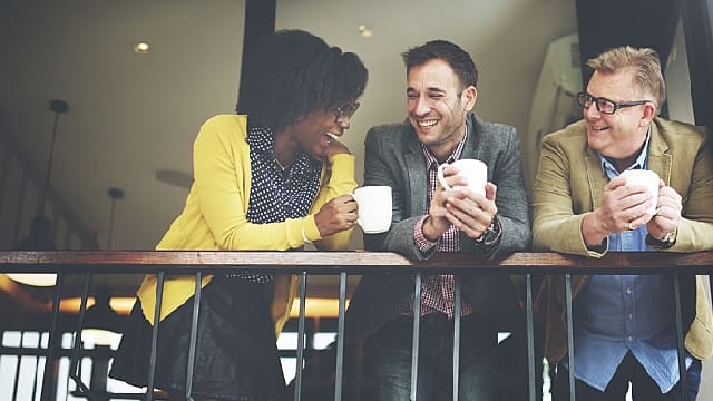 Grupo de amigos reunidos riendo y tomando café