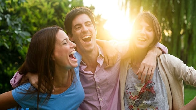 Friends laughing and hugging each other outdoors 