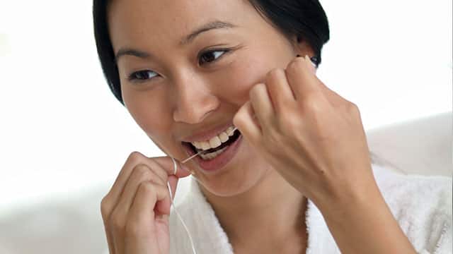 A woman is flossing her teeth