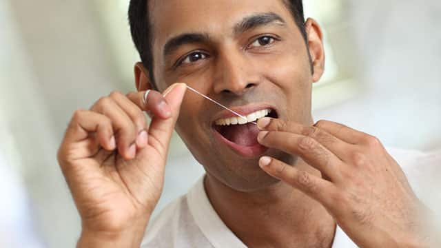 A man is flossing his teeth