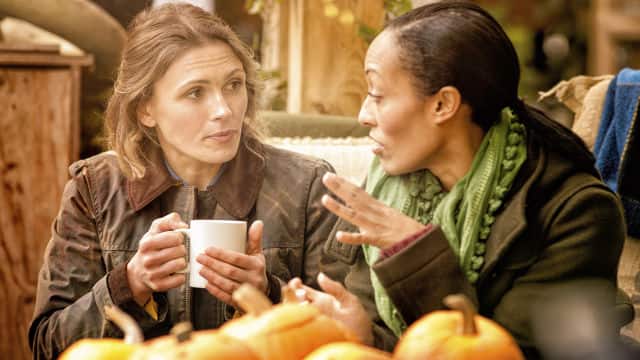 two woman chatting while enjoying a cup of coffee