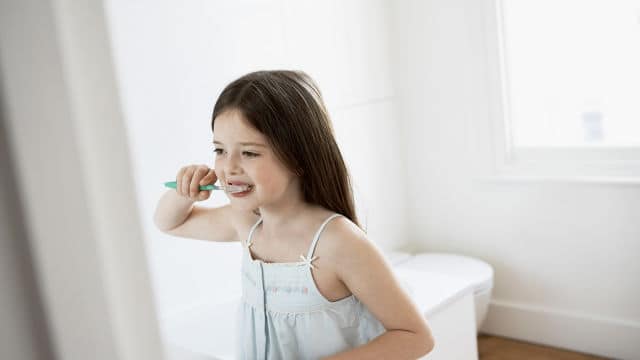a girl brushing her teeth with Colgate toothpaste