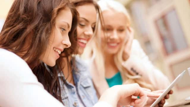 three women smiling brightly while looking at a chart