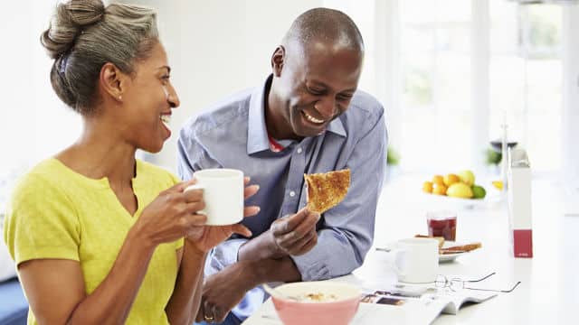 a man and a woman smiling brightly while enjoying their breakfast