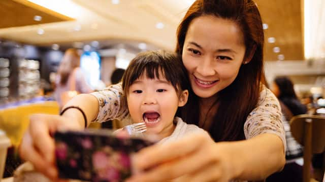 Mujer y su hija miran celular 