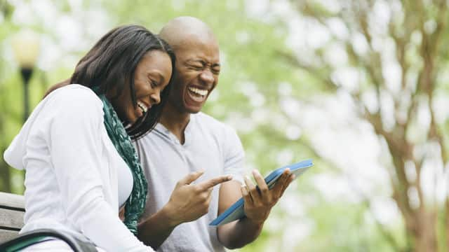 Mujer y hombre sonriendo mientras miran una tablet