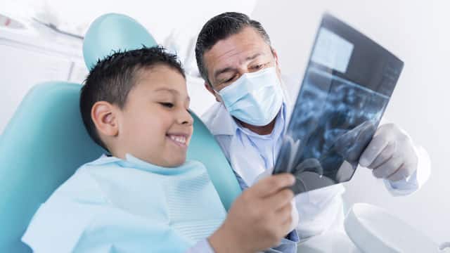 Odontólogo enseñando radiografia a un niño