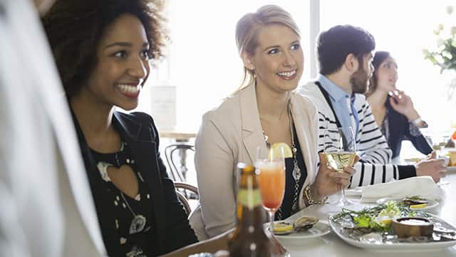 a group of people smiling while having lunch