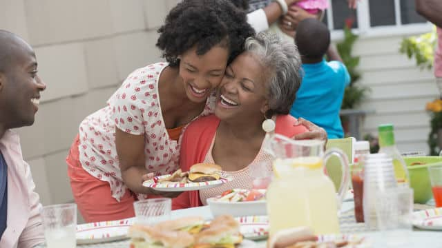 Daughter and mother smiling while enjoying a family meal