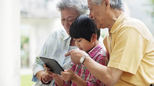 grandparents and grandkid smiling looking at the tablet