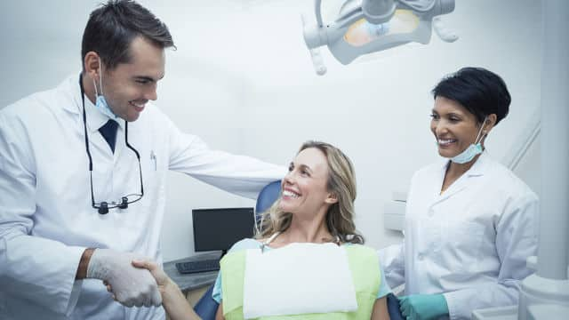 Paciente agradecida y dentista sonriendo en consulta odontológica