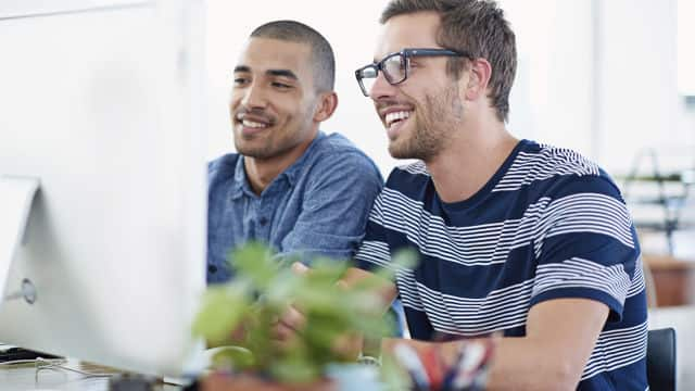 two men smiling while looking at the monitor