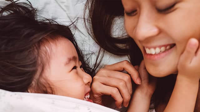 Madre e hija sonrientes bajo las cobijas