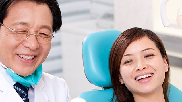 Dentist introducing mouth wash to patient Senior male Dentist and female patient smiling at something off camera.