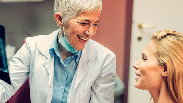 Happy female Dentist talking with a new patient.