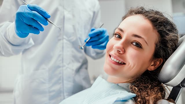 Smiling young woman receiving dental checkup. 