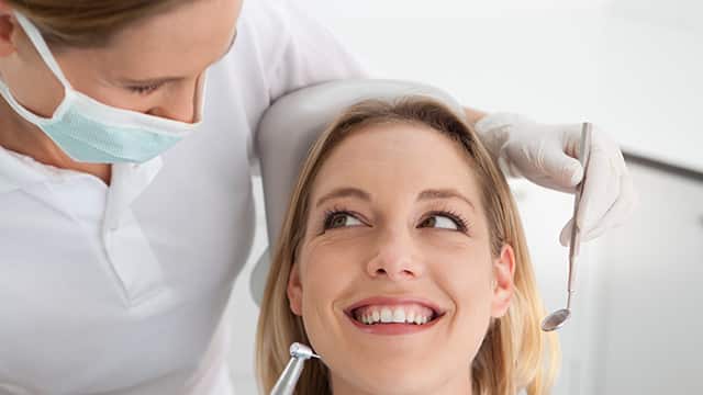 Female Dentist at work on a smiling woman patient in office.