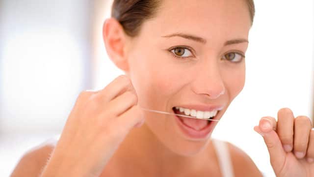 a woman is cleaning between her teeth by flossing