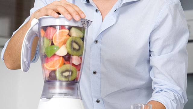 A man is making a smoothie in a blender close-up of a man making a smoothie in a blender