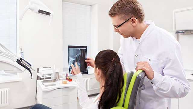 A female patient and male dentist are looking at the ex ray