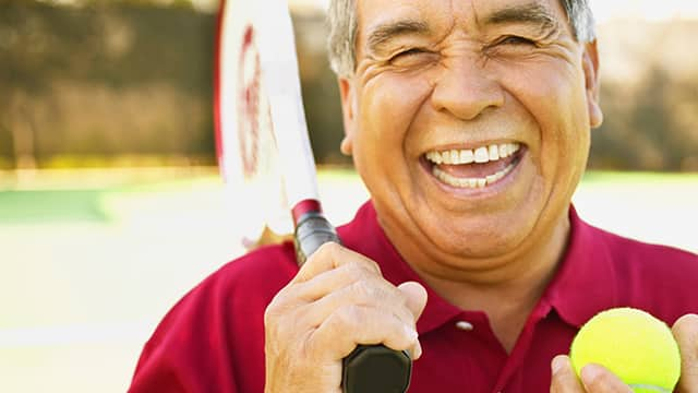 Hombre sonriendo y jugando tennis 