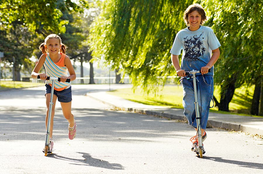 Boy and girl riding scooters