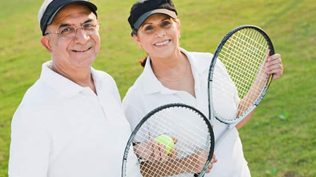 Older couple are holding tennis rackets