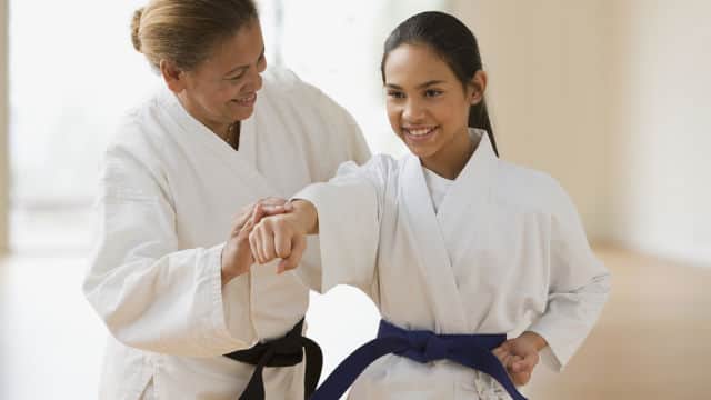 A martial arts instructor and student smiling while practicing
