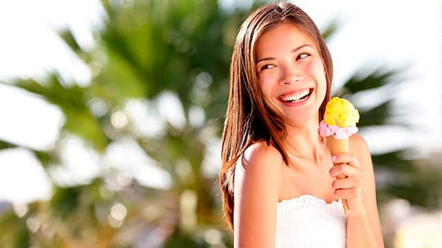 Mujer joven sonriendo y comiendo helado