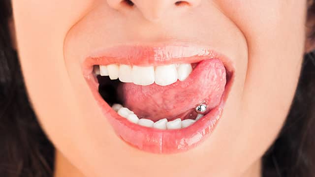 A close up of a woman's mouth with pierced tongue