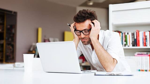 Man in glasses and white shirt researching on laptop computer
